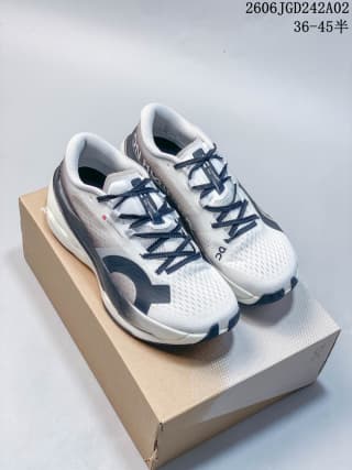 Pair of ON Cloudboom Max shoes displayed on a shoe box in a white, gray, and black colorway.