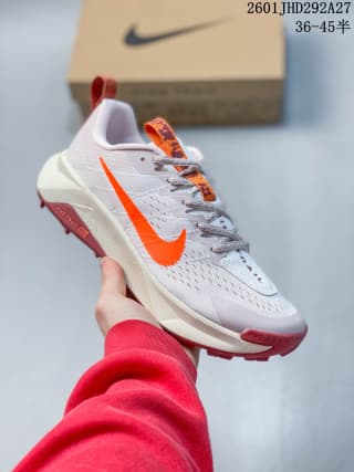 White Nike trail running shoe with a bright orange Swoosh and red outsole details.