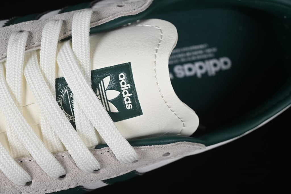 Close-up of the Adidas tongue label, white laces and dark green lining