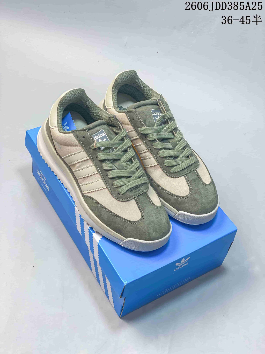 Sage green and cream adidas SL 72 sneakers with mustard side accents, shown on a blue box
