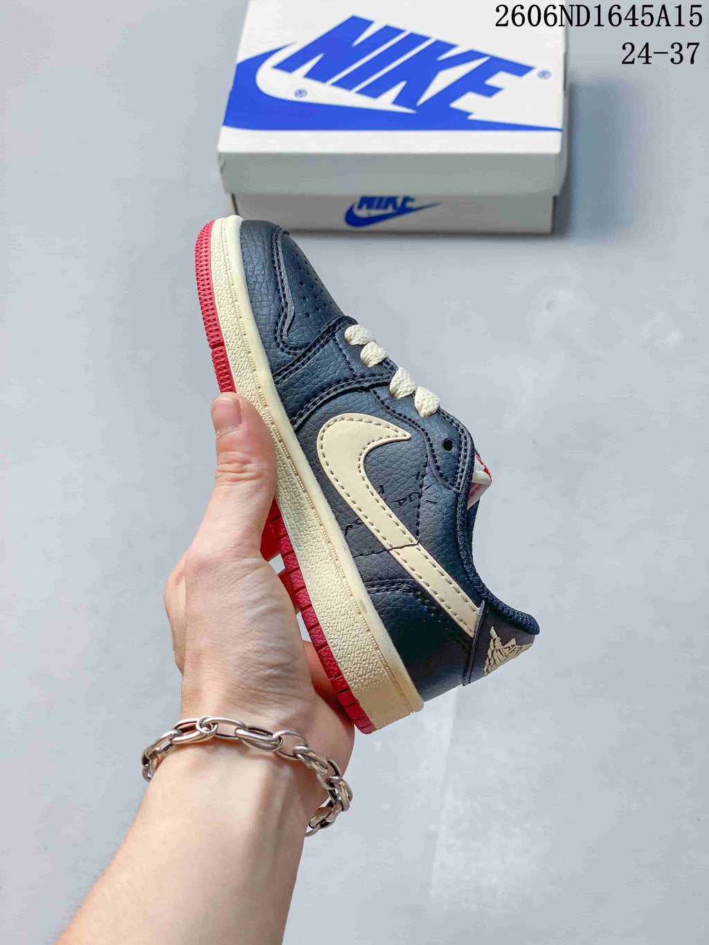 Side profile of a dark navy low-top sneaker with a cream-colored side panel and red outsole
