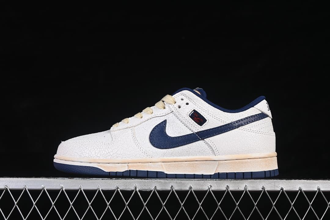 Side view of off-white and navy Nike SB Dunk Low sneakers with cream laces