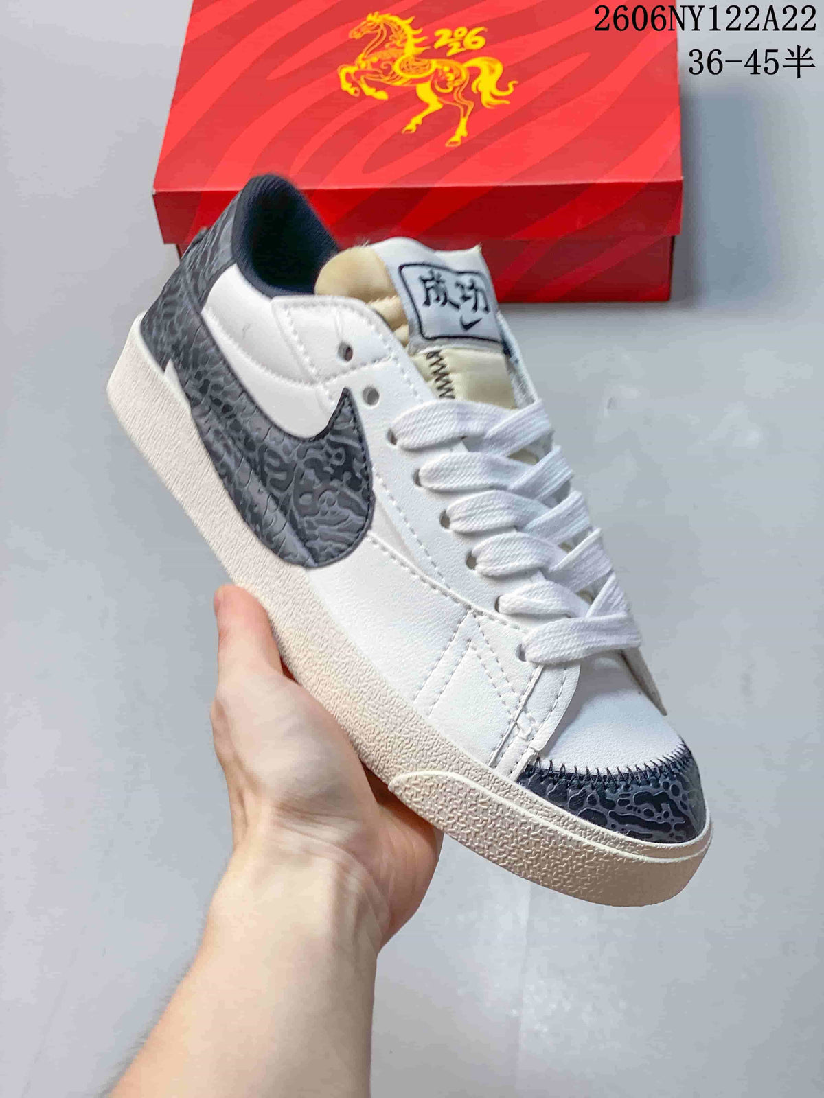 Angled view of the white sneaker with dark gray patterned Swoosh, toe, and heel details.