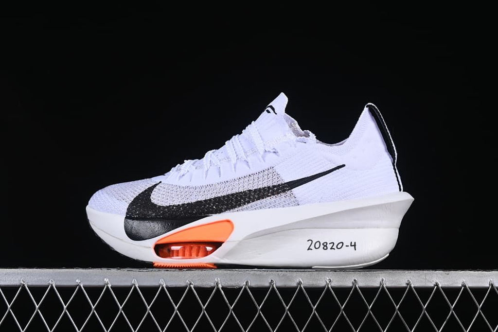 Side view of a white Nike running shoe with black Swoosh and orange midsole accents