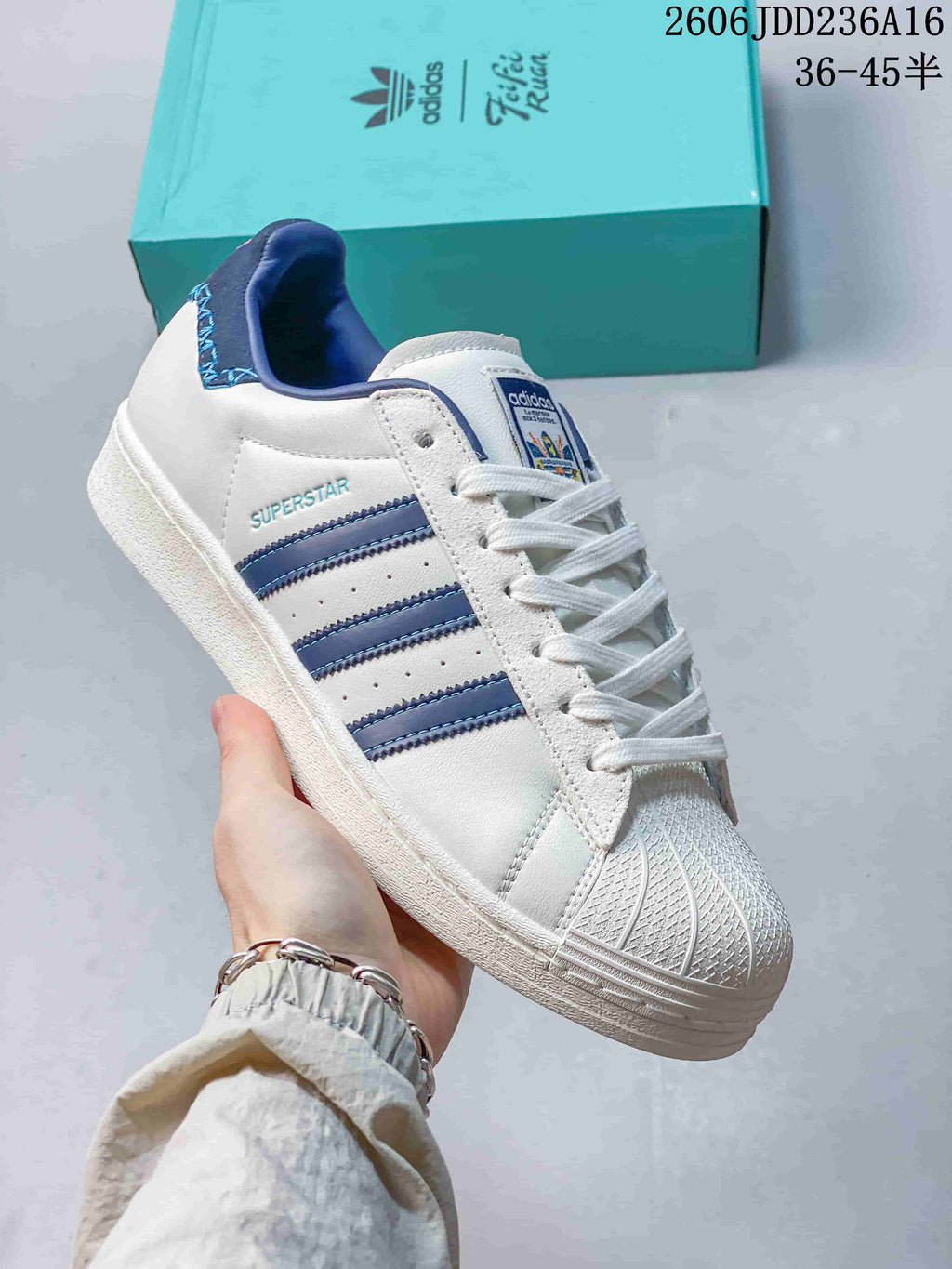 Angled view of a white Adidas Superstar with blue stripes and shell toe.