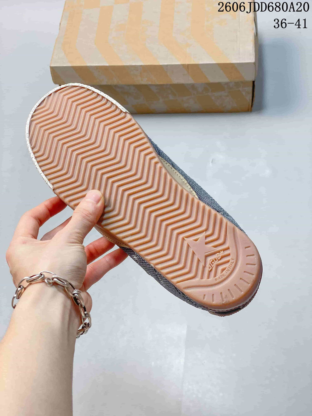 Underside of a sneaker showing a peach-toned sole with a zigzag tread pattern