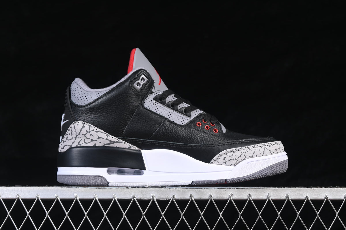 Side profile of a black Air Jordan 3 with grey cement-pattern overlays and red accents