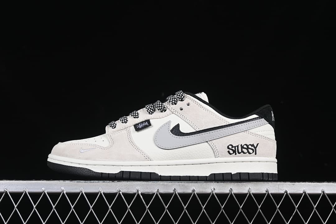 Side profile of an off-white and grey low-top sneaker with patterned laces and Stüssy-style side branding