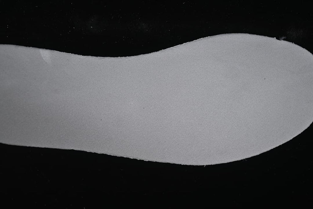 Removable-looking shoe insert photographed on a dark background