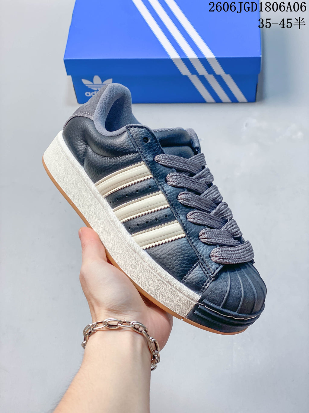 Angled side view of the dark grey sneaker with off-white stripes, grey laces, and a shell toe.