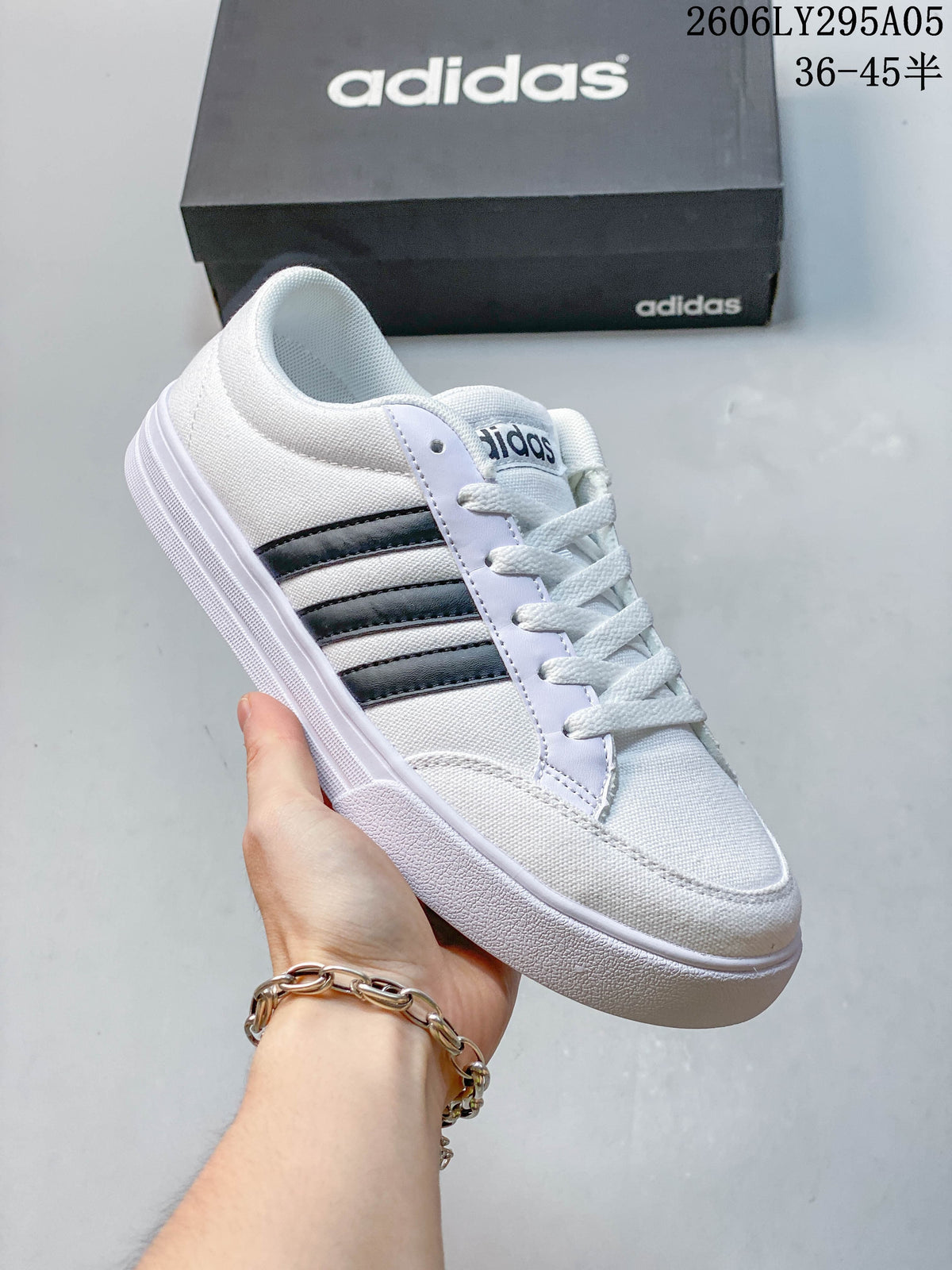 Side view of a white adidas low-top sneaker with dark stripes and a white outsole.