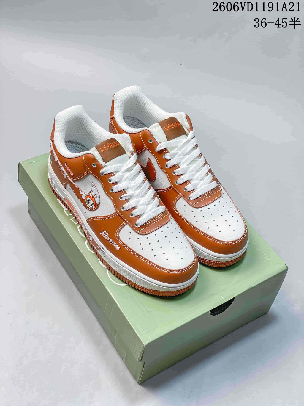 Pair of brown-and-white Nike Air Force 1 Low-style LABUBU sneakers on a green printed box