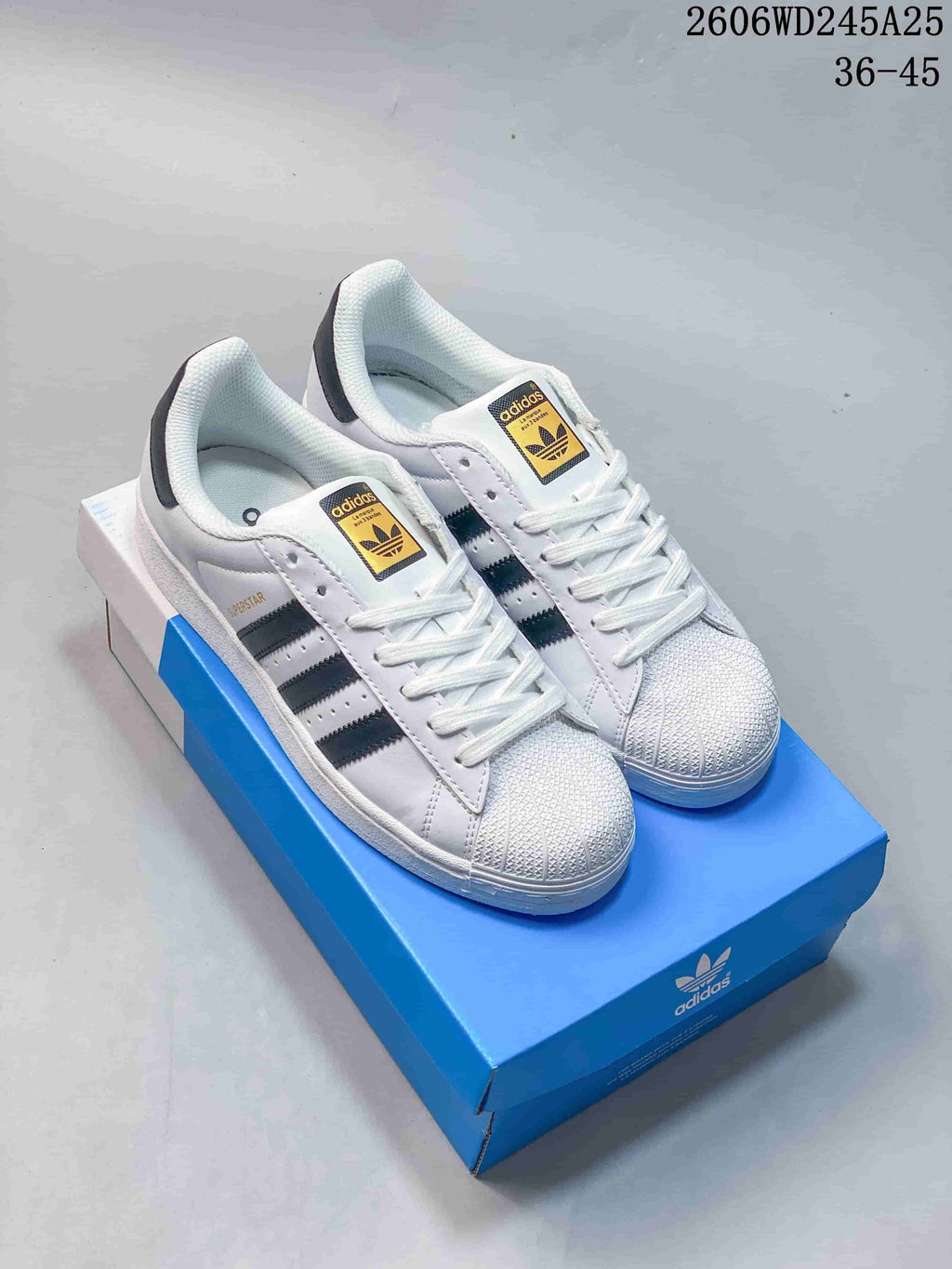 Pair of white adidas Superstar low-top sneakers with black stripes and textured shell toes