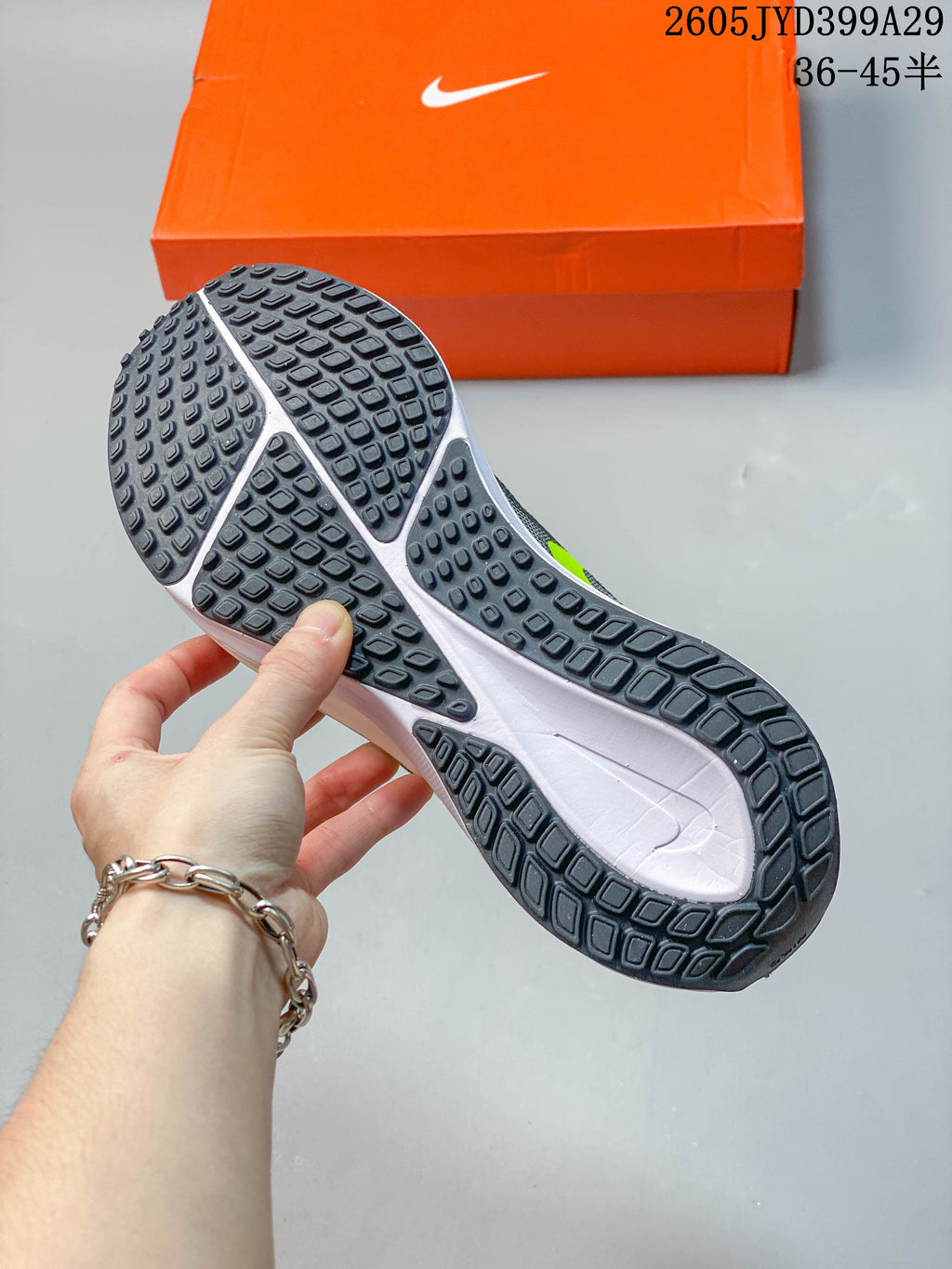 Underside view showing the dark patterned outsole of a gray running shoe.