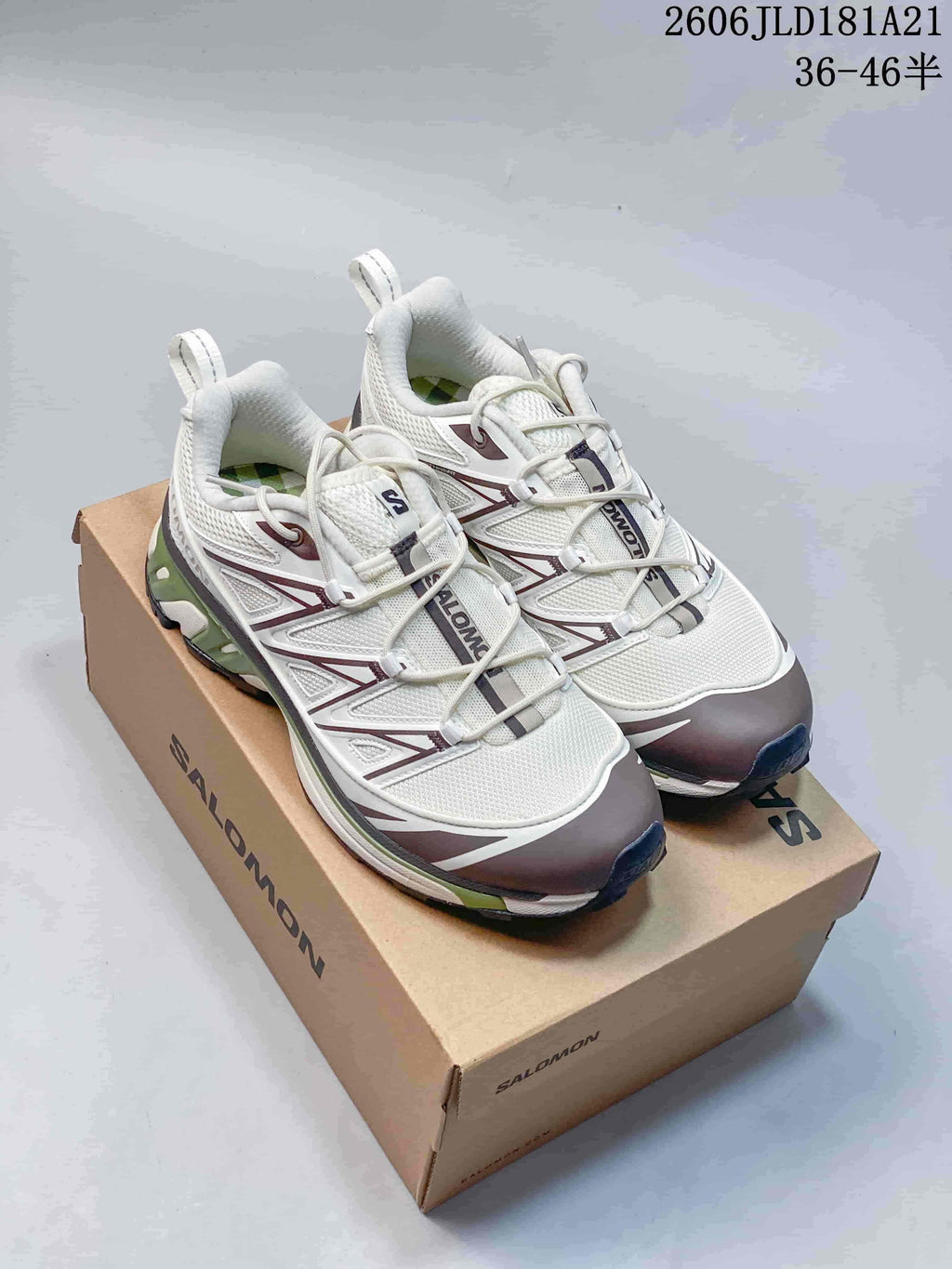 Pair of light-colored Salomon XT-6 Expanse sneakers with dark and green accents, shown on a shoe box.