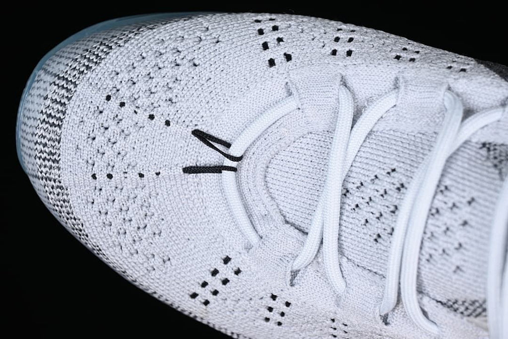 Top close-up of the knit toe box, lace area, and small black details.