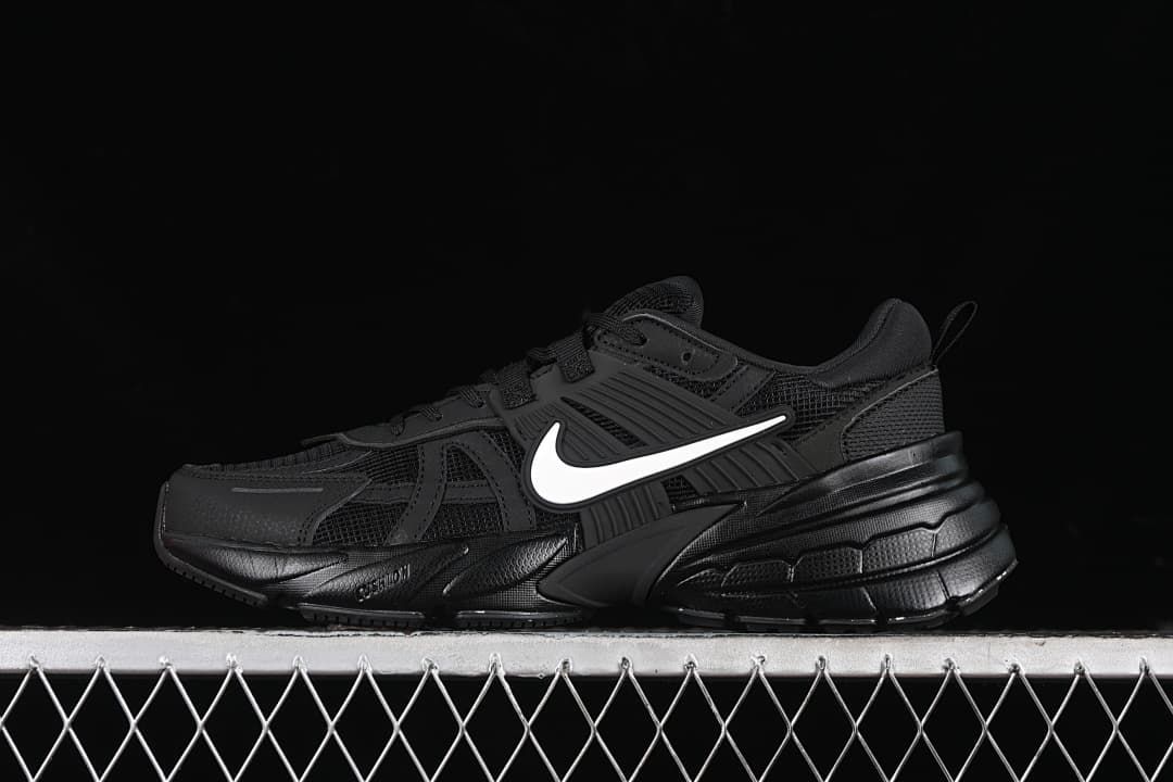 Black Nike V2K Run sneaker with a white Swoosh, shown in side profile.