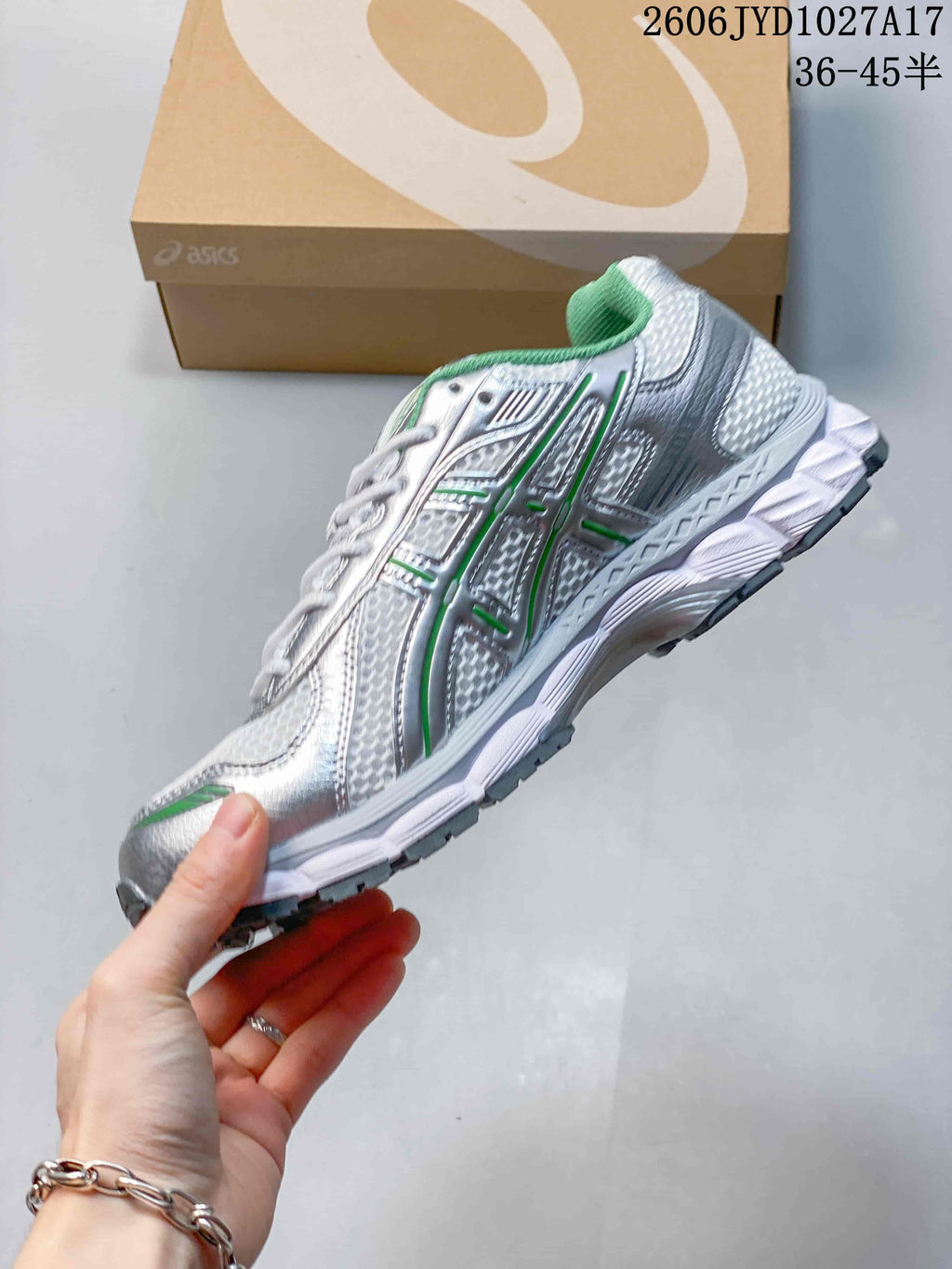 Side view of a silver-toned lace-up sneaker with green detailing