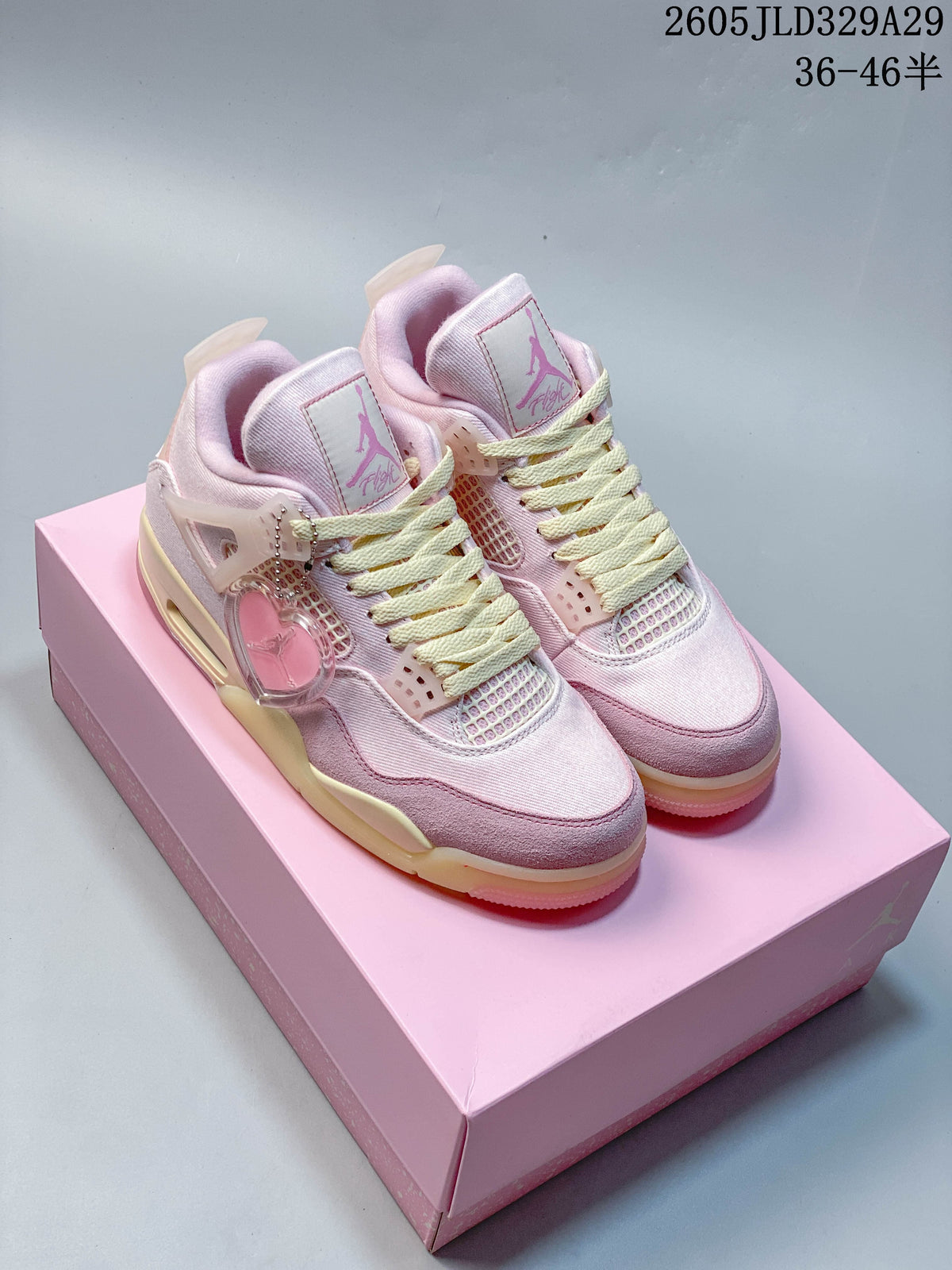 Pair of pink Jordan Air Jordan 4-style mid-top sneakers with pale laces and a heart-shaped accessory.