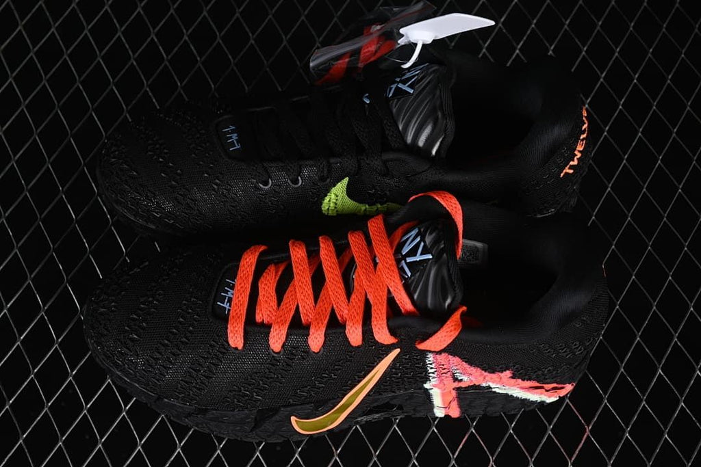 Pair of black low-top basketball shoes with contrasting orange-red laces and side accents.