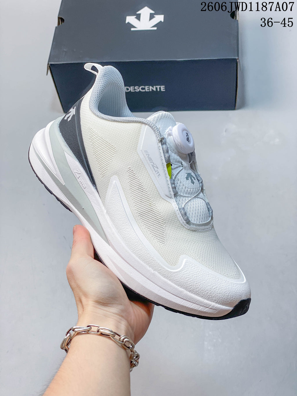 Angled side view of the white DESCENTE shoe with dial closure.