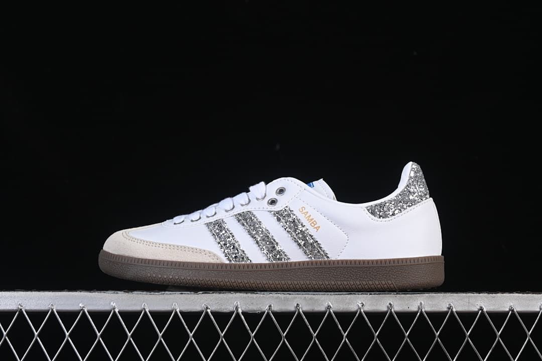 Side view of a white adidas Samba OG sneaker with silver glitter-effect stripes and heel, beige toe overlay, and gum-brown outsole.