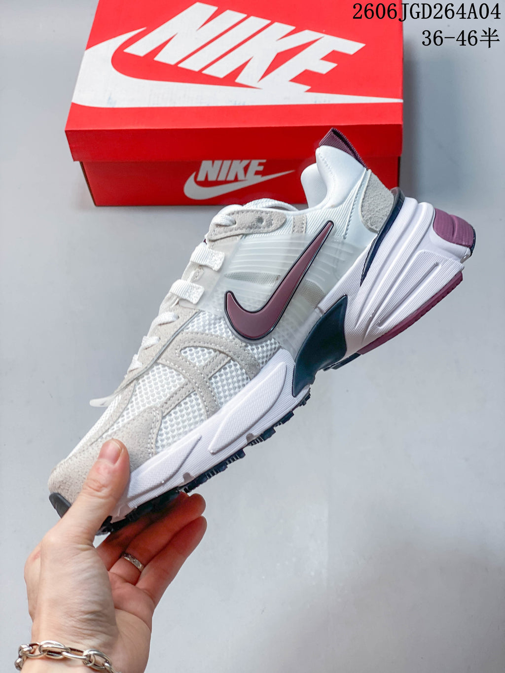 Side view of a white Nike V2K Run sneaker with gray overlays and a plum Swoosh