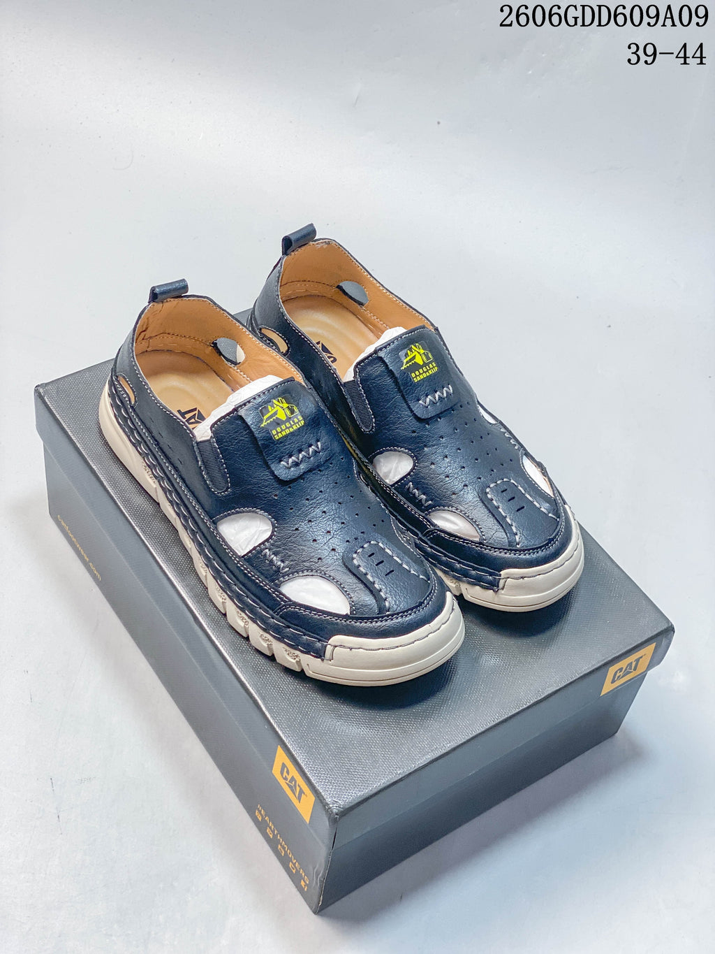 Pair of navy CAT-branded fisherman sandals shown on a shoe box; image overlay shows 2606GDD609A09 and sizes 39–44.
