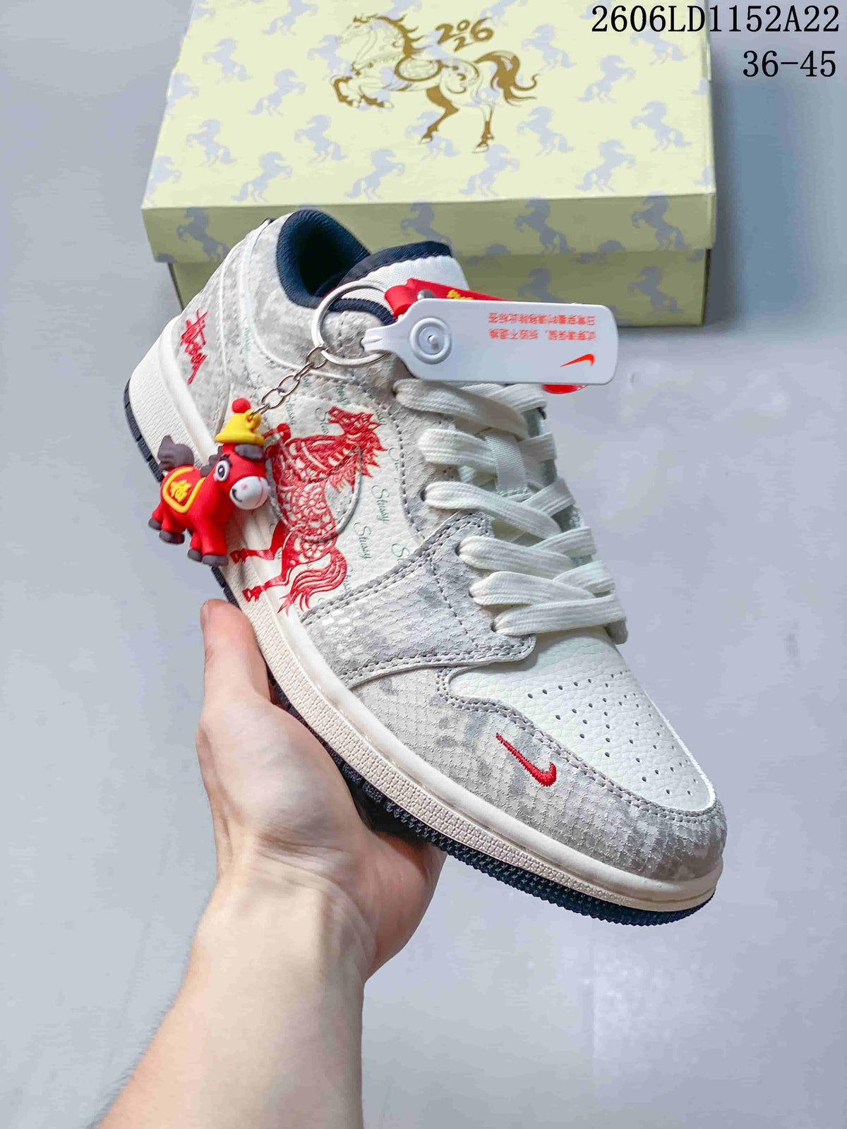 Angled view of a Jordan Air Jordan 1 Low sneaker with red decorative side graphics, white laces, and grey patterned panels.