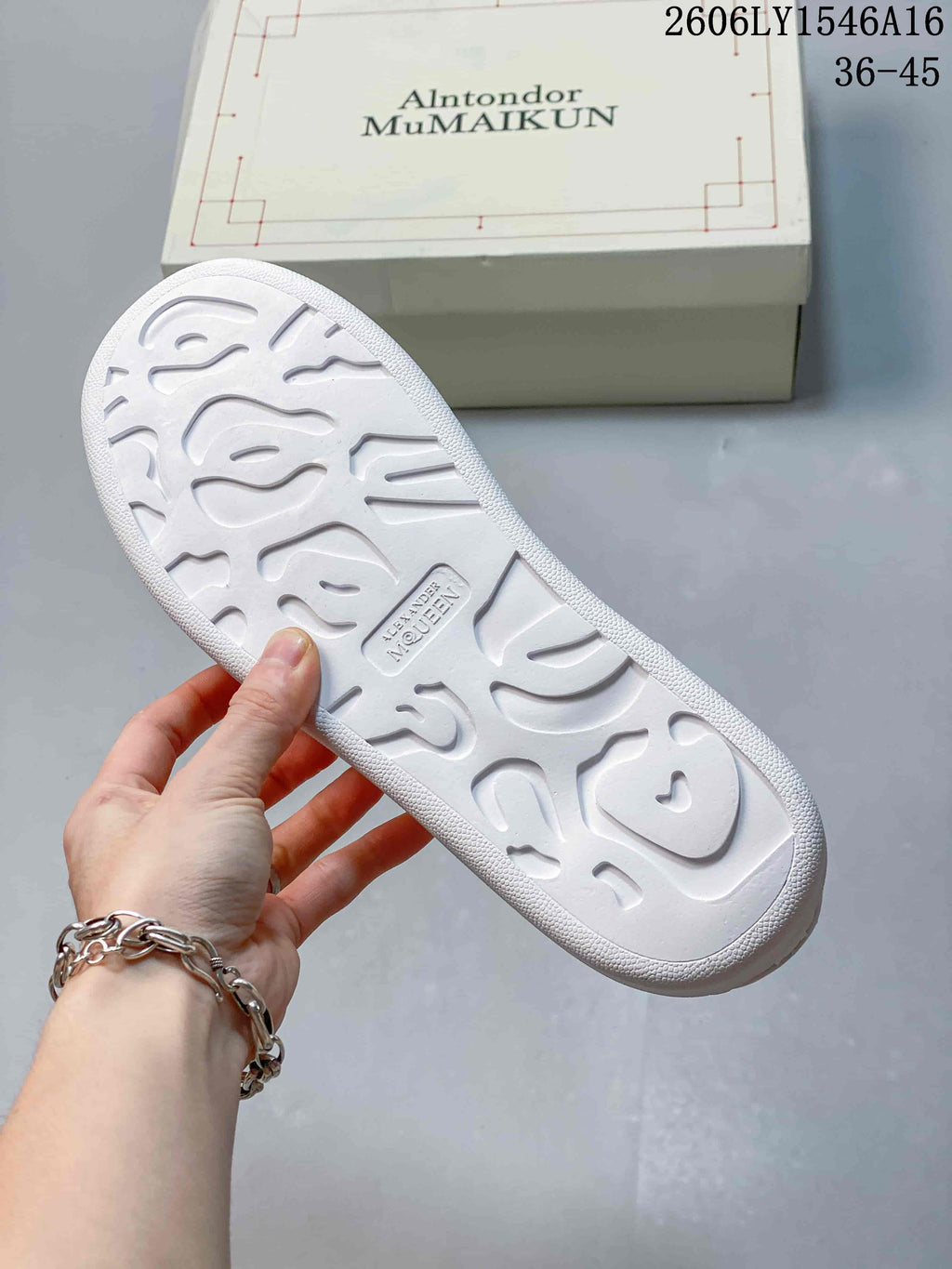 Textured outsole of a white sneaker, with the shoe box in the background.