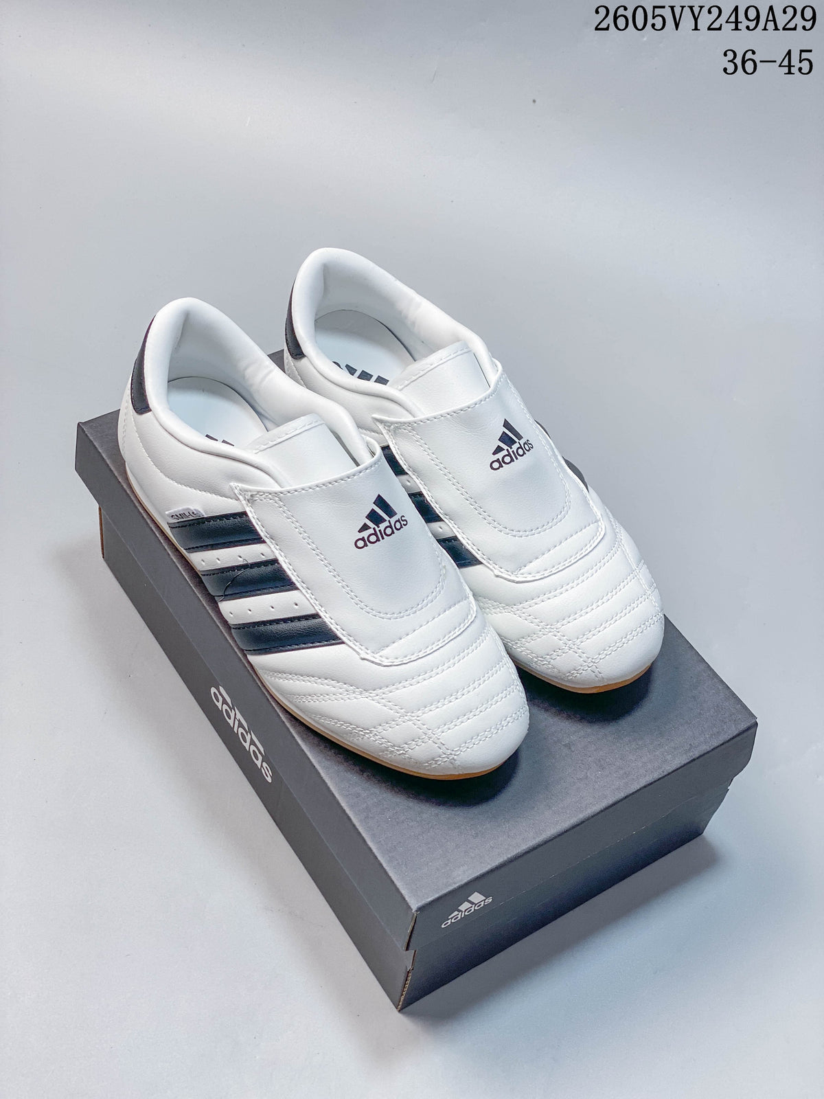 Pair of white low-top shoes with broad instep straps and dark side stripes.