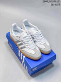 White adidas Samba low-top sneakers with silver stripes and gum-colored soles on a blue shoebox.