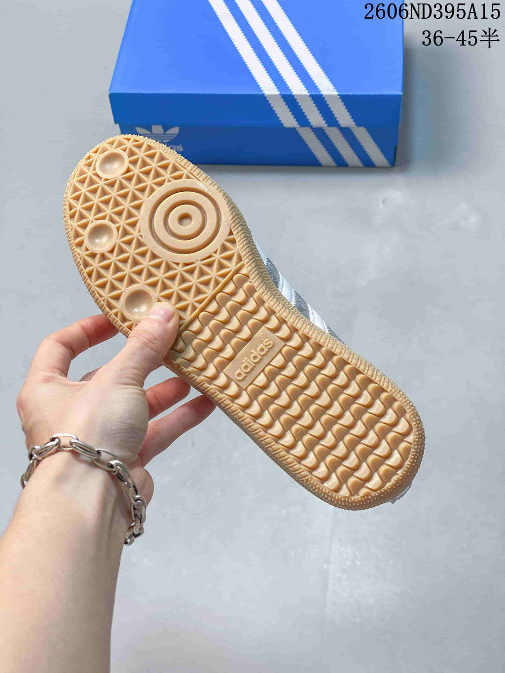 Close view of the patterned gum-colored outsole on a silver Adidas Originals sneaker