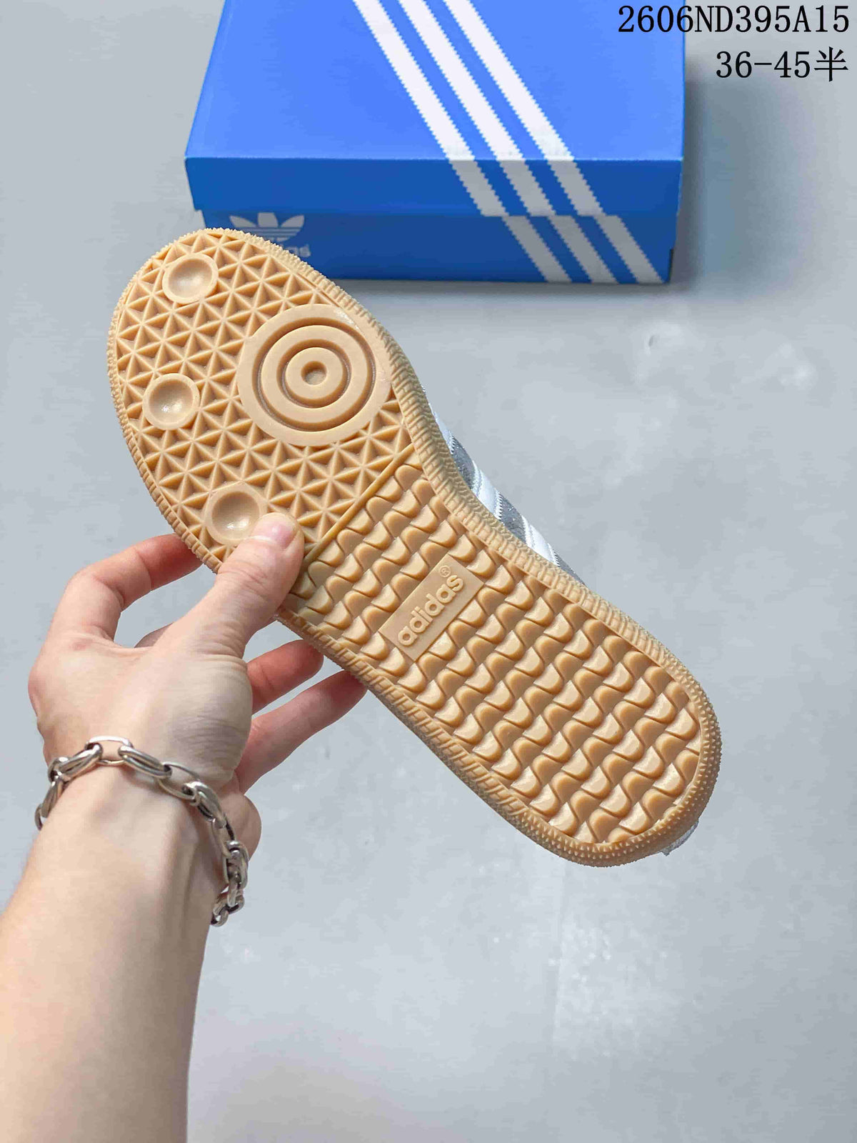 Close view of the patterned gum-colored outsole on a silver Adidas Originals sneaker