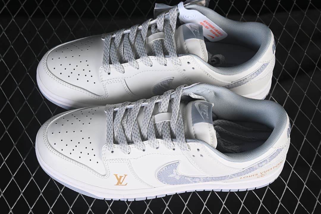 Pair of white low-top sneakers showing gray patterned laces, patterned Swooshes, and gold-tone details