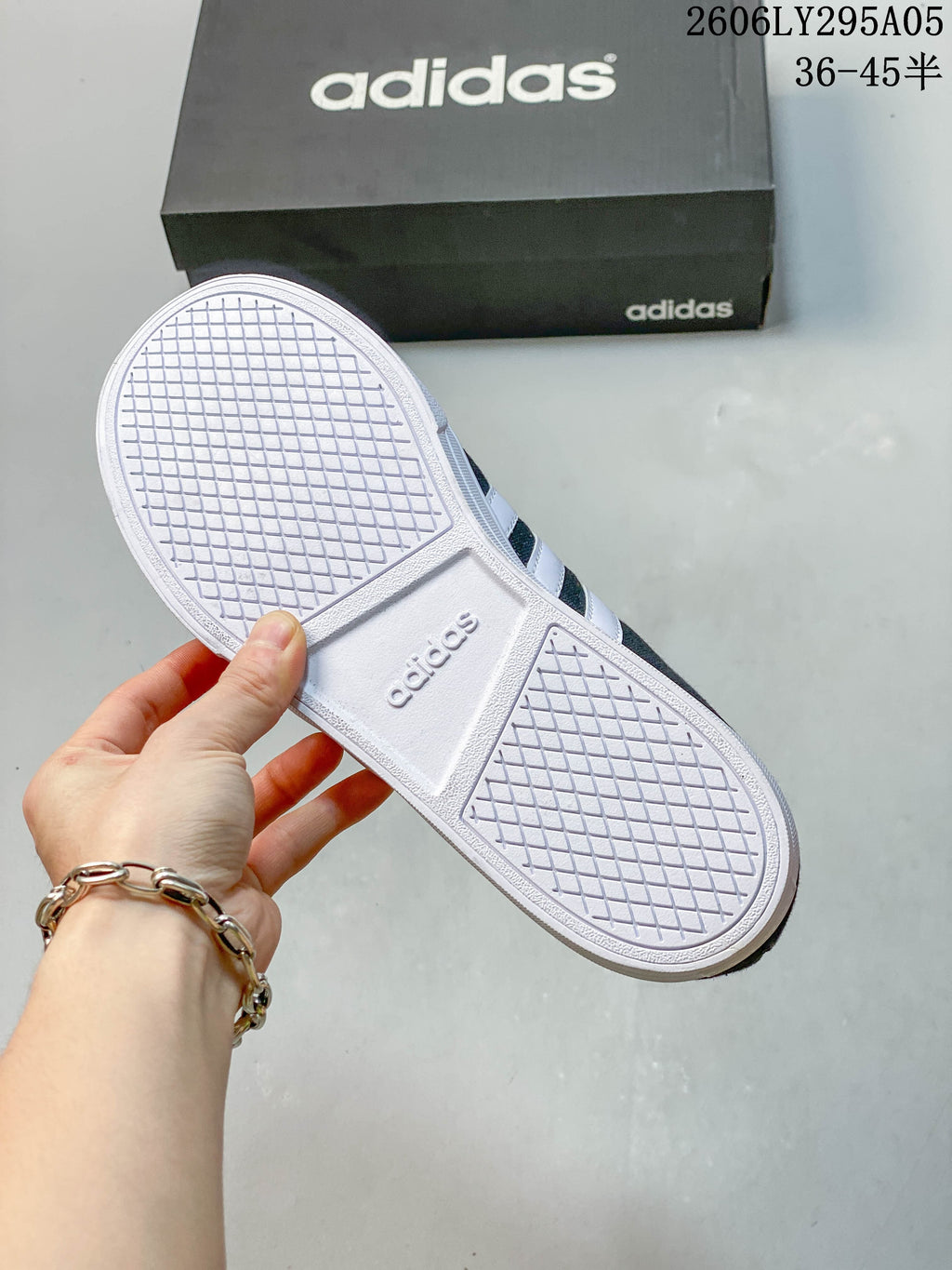 White rubber outsole with a textured tread pattern on an Adidas low-top sneaker.