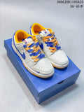 Pair of white low-top Nike SB Dunk sneakers with blue and yellow accents displayed on a blue box
