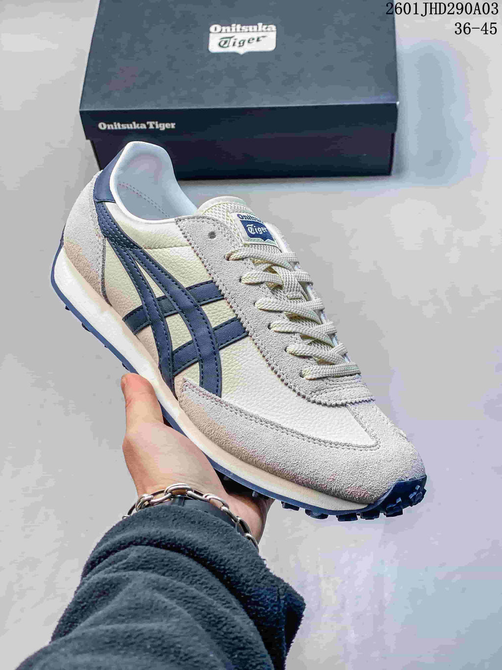 Close-up of a light-colored Onitsuka Tiger EDR 78 sneaker with navy side stripes and a shoebox behind it.
