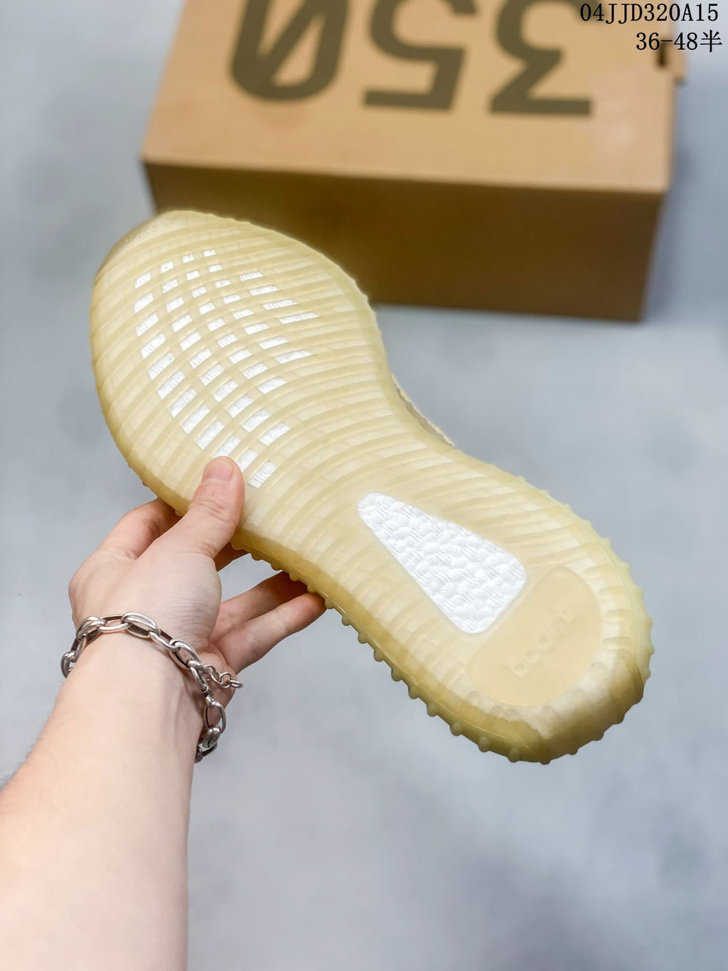 Underside of a Yeezy Boost 350 V2 sneaker showing its translucent ribbed sole; image overlay shows sizes 36–48.5 and style code 04JJD320A15.