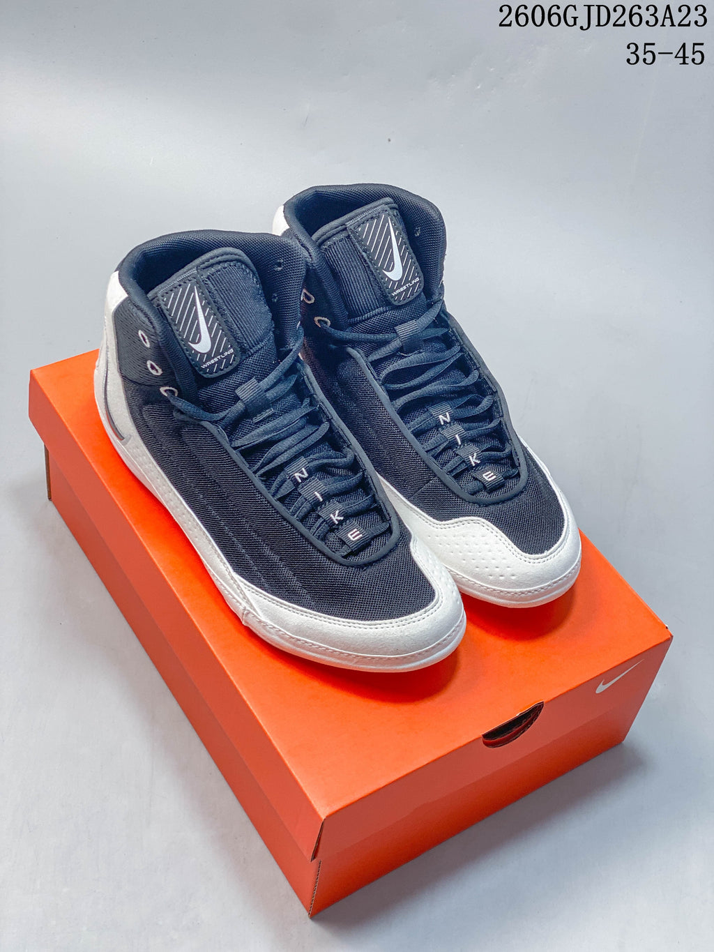 Pair of dark navy and white Nike Inflict 4 wrestling shoes on an orange shoebox