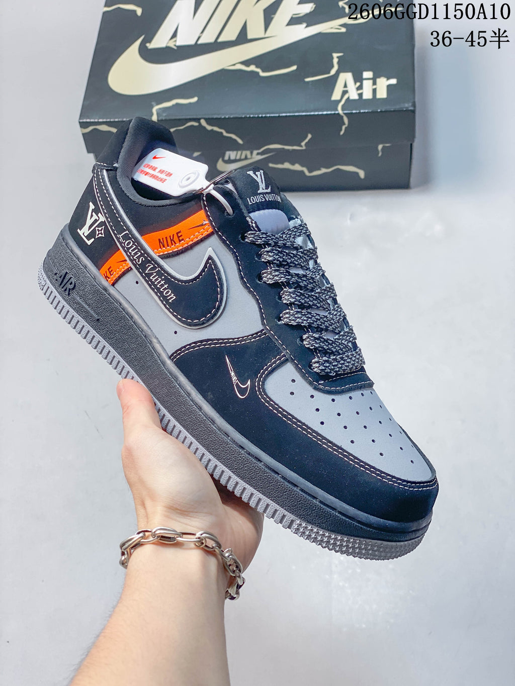 Angled side view of a navy and gray sneaker with orange accent panel and patterned laces