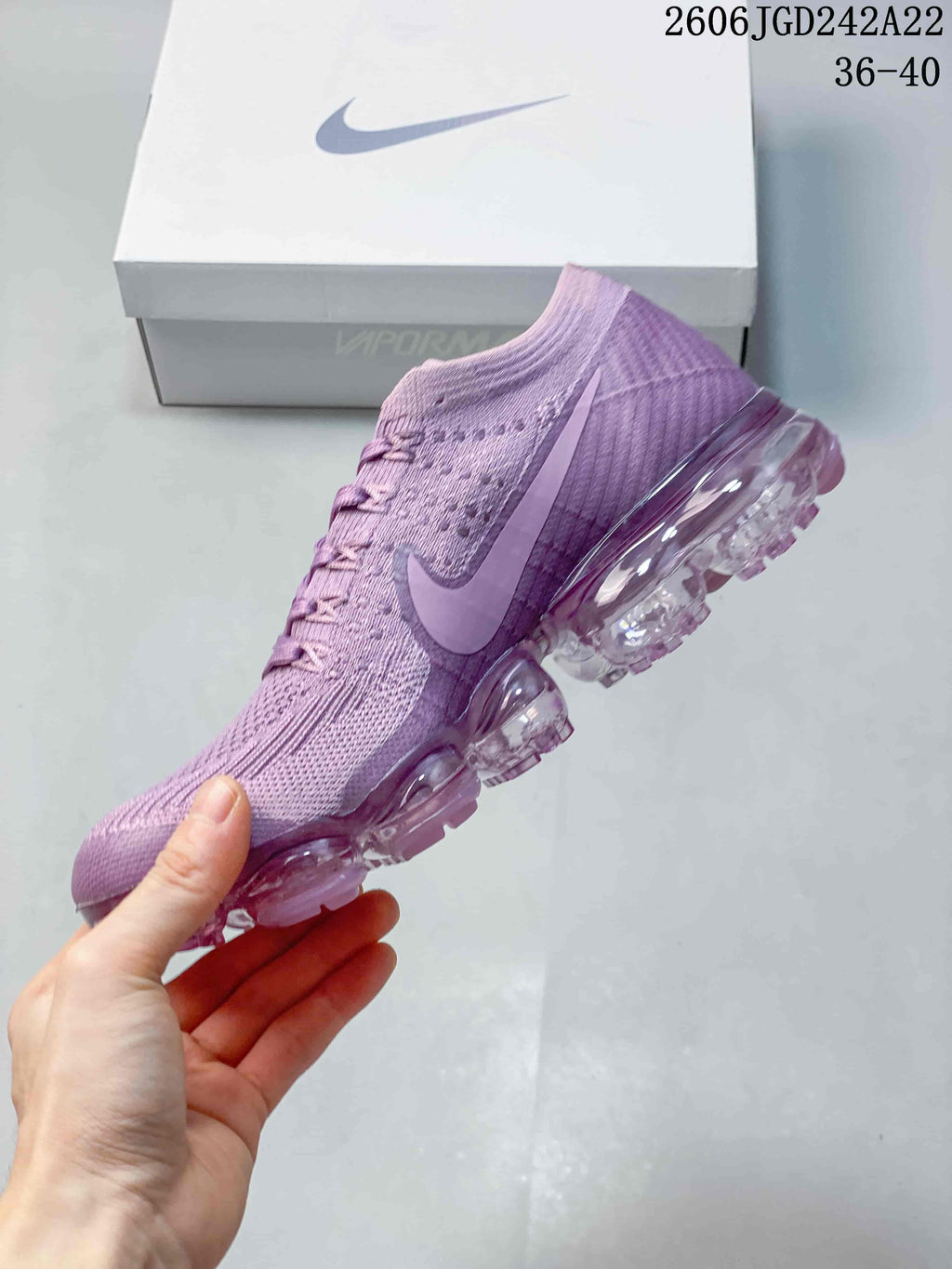 Side view of a purple Flyknit-style sneaker with a Swoosh and transparent segmented sole; image displays the size range 36–40.