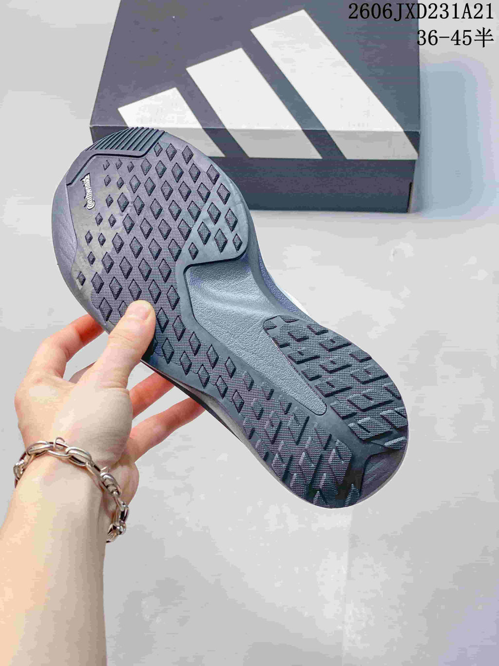 Close-up of the patterned outsole on a white and grey running shoe.