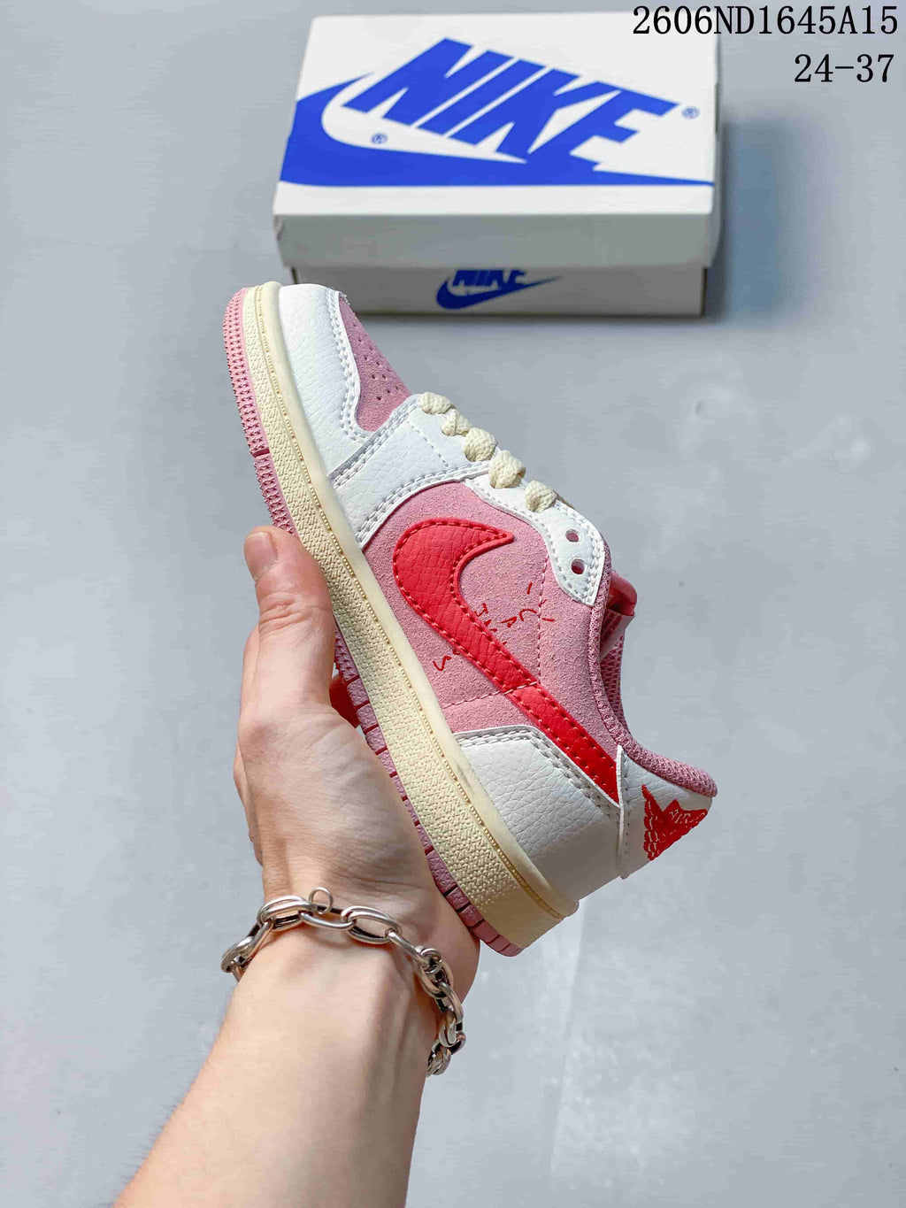 Side view of the low-top sneaker with pink panels, a red side detail, and a cream-colored midsole.