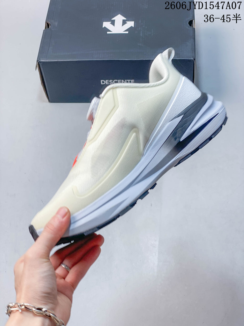 Side profile of a cream DESCENTE low-top shoe with a layered white and gray sole.