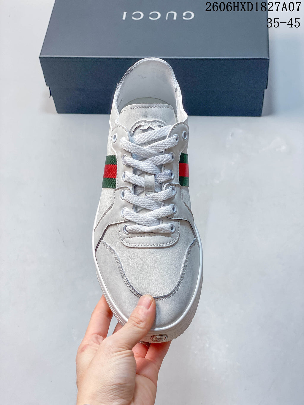 Front view of a white lace-up sneaker with green-and-red side stripes.