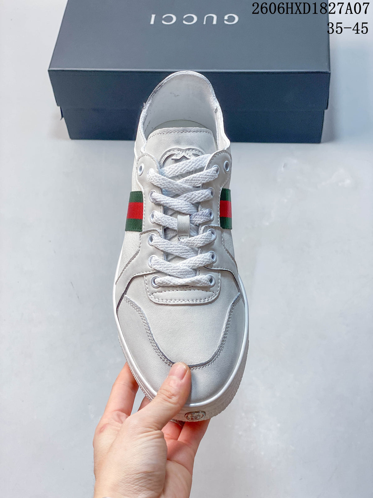 Front view of a white lace-up sneaker with green-and-red side stripes.