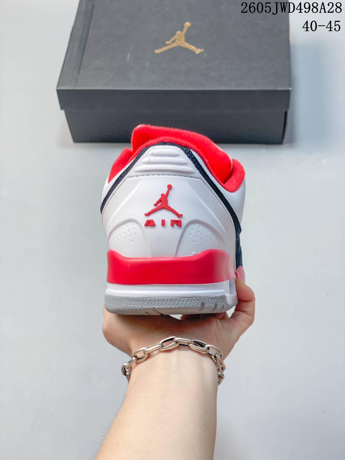 Rear view of a white Jordan sneaker with red heel accents