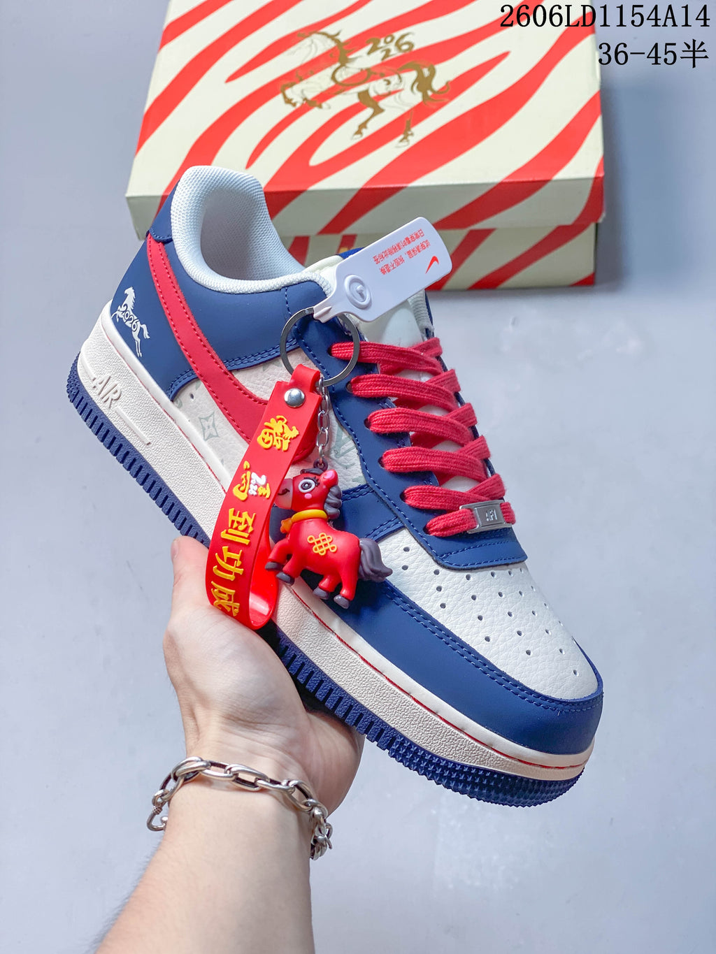 White and blue low-top sneaker with red laces, graphic detailing and a dangling red charm