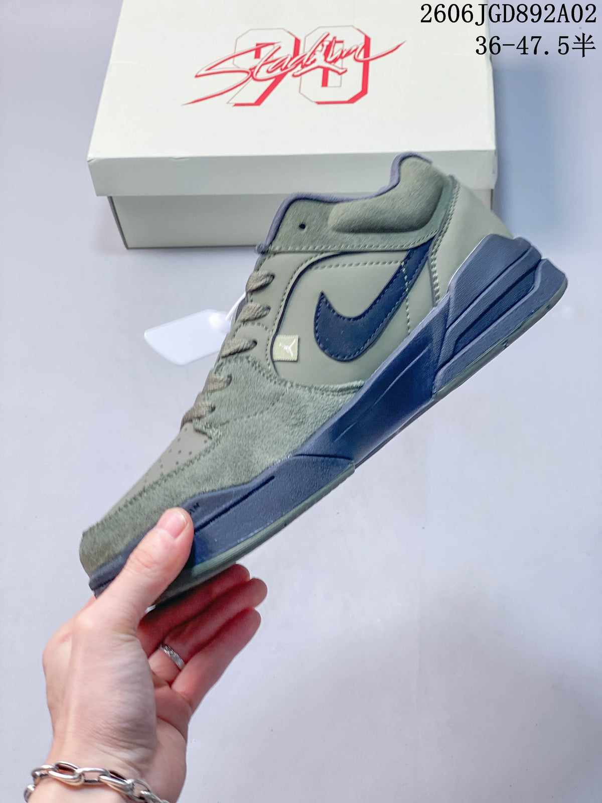 Side profile of a sage-green Jordan Stadium 90 sneaker with navy Swoosh and midsole details.